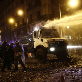 Un grupo de policías antidisturbios junto a la tanqueta de agua a presión durante los altercados que se están produciendo en Barcelona este viernes. /EFE