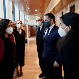 La presidenta de la Comunidad de Madrid, Isabel Díaz Ayuso (i) conversa con la portavoz de Vox en la Asamblea, Rocío Monasterio (d) en presencia del líder partido de ultradereha, Santiago Abascal (2d), en los pasillos de la Asamblea de Madrid, en una f