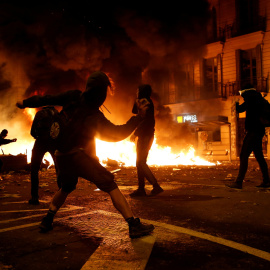 Un grupo de radicales en una barricada incendiada lanzando objetos a los Mossos en Barcelona. /REUTERS