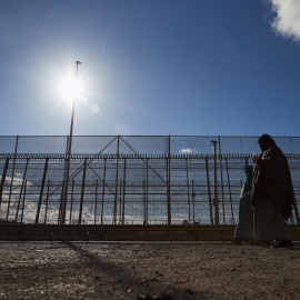 Unas melillenses pasean junto a la valla este domingo, tras los intentos de cruce masivo de estos días atrás.