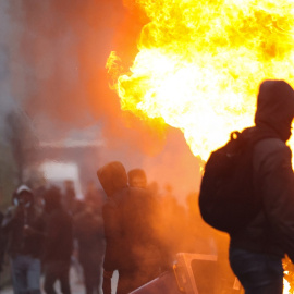 Un hombre camina frente a un contenedor en llamas mientras estallan los enfrentamientos a causa de las medidas restrictivas en Bruselas el 21 de noviembre de 2021.