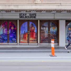 Una mujer pasa junto a un letrero de 'Stay Safe Melbourne' en una calle del centro de la ciudad.