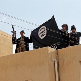Soldados iraquíes muestran una bandera del Estado Islámico mientras toman posición en un tejado de una vivienda de Mosul. - EFE