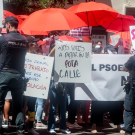 Varias personas con pancartas y paraguas rojos, frente a la policía, protestan durante una concentración, en la sede del PSOE en calle Ferraz, a 2 de junio de 2022, en Madrid (España).