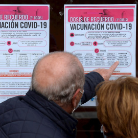 Dos personas observan un cartel con las pautas para recibir la tercera dosis de Pfizer en Valladolid este miércoles en el que el Ministerio de Sanidad ha recomendado limitar el número de participantes en los "eventos públicos y sociales", especialm