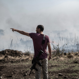 Un hombre armado se encuentra cerca de un incendio causado por ataques con misiles y drones en el Líbano. Imagen de archivo.
