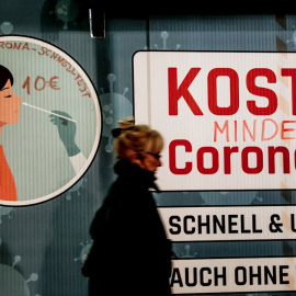 Una mujer pasea por delante de un anuncio de test PCR en Berlín.