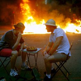 Dos hombres bromean jugando al ajedrez en medio de los disturbios que se están produciendo en Barcelona. /EFE