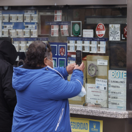 Varias personas en una administración de lotería de Navidad de la Puerta del Sol cuando quedan menos de tres semanas para el Sorteo Extraordinario de la Lotería de Navidad, a 7 de diciembre de 2021, en Madrid (España).