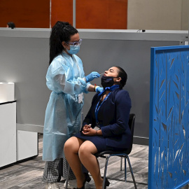 19/05/2021.- Una sanitaria realiza una PCR para detectar el coronavirus a una azafata de Fitur en Ifema.