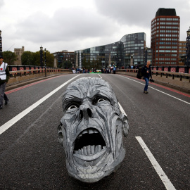 Los activistas ecologistas dejan en mitad del Puente Lambeth (Londres) la escultura de un rostro con cara de dolor. REUTERS