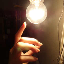Mano tocando una bombilla.