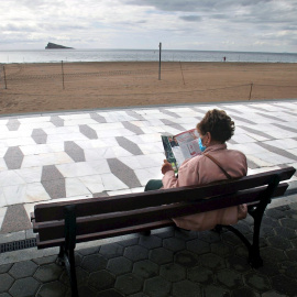 Una persona descansa en el paseo de la playa de Levante de Benidorm, prácticamente desierta