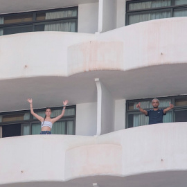Dos jóvenes que permanecen en aislamiento en el hotel Palma Bellver de Palma saludan desde los balcones de sus habitaciones, este martes 29 de junio en Palma de Mallorca.