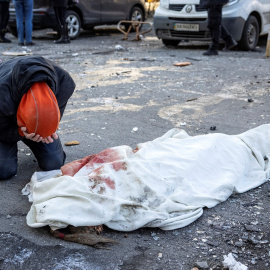 Una persona llora junto a un cuerpo envuelto cerca de un edificio residencial que fue alcanzado por los escombros de un cohete derribado en Kiev, a 17 de marzo de 2022.
