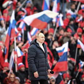 La multitud ondea banderas rusas mientras el presidente ruso Vladimir Putin camina para pronunciar un discurso durante un concierto celebrado para conmemorar el octavo aniversario de la anexión de Crimea por parte de Rusia en el estadio Luzhniki.