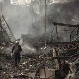 Un periodista camina bajo los escombros de un almacén logístico bombardeado en Brovary, junto a Kiev, durante una visita oficial para la prensa