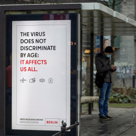 Un cartel advierte del riesgo de contagio de la covid-19 para cualquier edad, en una parada de autobús en Berlin.