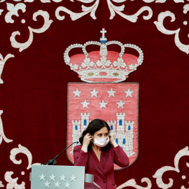 La presidenta madrileña, Isabel Díaz Ayuso, se coloca la mascarilla mientras preside la ceremonia de toma de posesión de los nuevos consejeros de la Comunidad de Madrid, este lunes, en la Real Casa de Correos.
