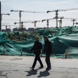 Dos trabajadores migrantes caminan cerca de una obra en Pekín. EFE/EPA/WU HONG