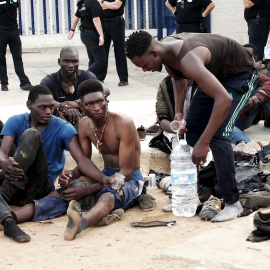 Migrantes en MelillaUn grupo de inmigrantes subsaharianos aguardan tras conseguir saltar la valla fronteriza de Melilla este jueves.