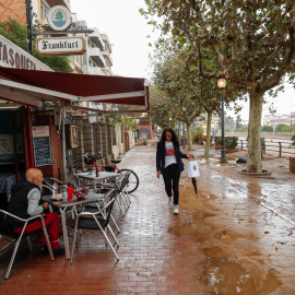 23/10/2019.- Una mujer camina junto a un bar por una calle cubierta de lodo después de las inundaciones causadas por lluvias torrenciales en Arenys de Mar. REUTERS / Albert Gea