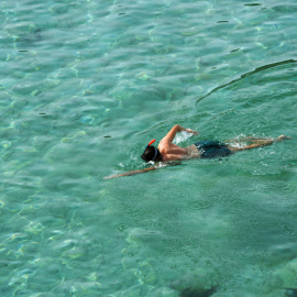 Un bañista nada en la cala de Alcalfar en Menorca, este miércoles 26 de octubre de 2022, donde se pueden llegar a alcanzar los 33 grados.