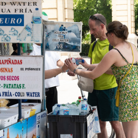19/07/2024 Unos turistas compran agua en un puesto callejero de la ciudad de Sevilla. Foto de archivo.