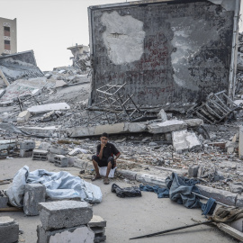 Un palestino sentado junto a los escombros de un edificio tras un ataque israelí
