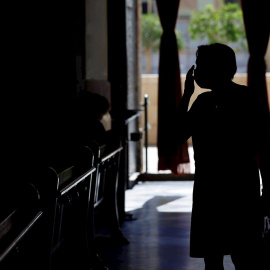 Una mujer, protegida con una mascarilla, se santigua al entrar en la Basílica de Valéncia.