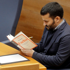 El conseller de Educación y Deportes de la Generalitat, Vicent Marzá, lee el libro 'Facha' durante la intervención del diputado de Vox, Jose María Llanos, en el debate en Les Corts Valencianes. (KAI FÖRSTERLING | EFE)