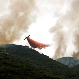 Continúa activo el incendio forestal de Llutxent (Valencia), que ha quemado más de mil hectáreas y ha obligado al desalojo de 2.500 personas. En la imagen una avioneta lanza agua con retardantes sobre el frente del incendio que se acerca a la localidad