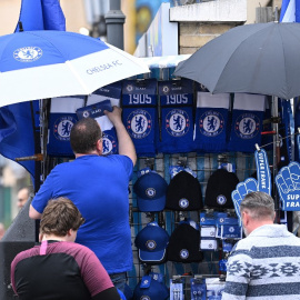 Un vendedor instala su puesto de mercadería fuera de Stamford Bridge antes del partido de fútbol de la Premier League inglesa entre Chelsea y Wolverhampton Wanderers, en Londres el 7 de mayo de 2022. Chelsea confirmó el sábado que un consorcio liderad
