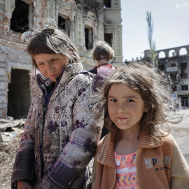 Dos niñas caminan por las ruinas de la ciudad devastada de Mariúpol (Ucrania) durante el Día de la Victoria, este 9 de mayo de 2022.