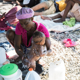 Una mujer baña a su bebé en un campamento en Puerto Príncipe, Haití. REUTERS