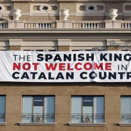 Una pancarta penjada de la façana d'un dels edificis de la Plaça de Catalunya amb la qual es critica la presència del rei Felip VI als actes d'homenatge del 17A.  EFE/ Andreu Dalmau.