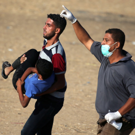 Dos hombres trasladan a un joven palestino herido durante las últimas protestas contra Israel. - REUTERS