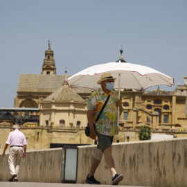 19/05/2022-Una persona se protege con una sombrilla del intenso calor mientras pasea este jueves 19 de marzo por el puente romano de Córdoba