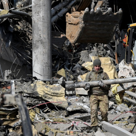 24/03/2022 Un militar ucraniano carga un fragmento de misil mientras sale de un edificio bombardeado de Kiev, a 24 de marzo