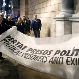 03/01/2020.- El presidente de la Generalitat Quim Torra (i) muestra la pancarta por la que la Junta Electoral Central le ha sancionado, ordenando que se le retire su credencial de diputado autonómico, lo que conlleva su inhabilitación. / EFE