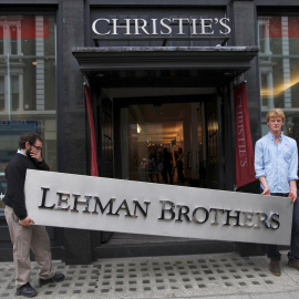 Dos empleados sujetan el letrero de la empresa Lehman Brothers. REUTERS/Andrew Winning