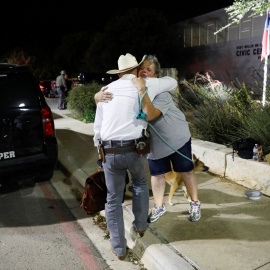 Una mujer que ofrece abrazos y oraciones abraza a un guardabosques de Texas fuera del Centro Cívico Ssgt Willie de Leon, donde los estudiantes habían sido transportados desde la Escuela Primaria Robb después de un tiroteo, en Uvalde, Texas , EE. UU. 24