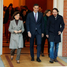 El primer ministro, Pedro Sánchez (C), camina junto a la vicepresidenta primera y ministra de Presidencia y Realciones con las Cortes, Carmen Calvo (i), y el vicepresidente de Derechos Sociales y Agenda 2030, Pablo Iglesias (d), momentos antes de posar p