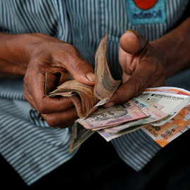 Un hombre maneja un fajo de billetes de rupias, en la ciudad india de Kolkata. REUTERS/Rupak De Chowdhuri