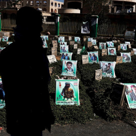 Un yemení camina entre los retratos de las tumbas de los últimos yemeníes, que supuestamente fueron asesinados en la guerra en curso del país, durante el aniversario de la Semana de los Mártires celebrada por los hutíes en un cementerio de Yemen