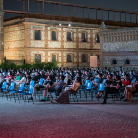 Un grupo de gente disfruta de una película proyectada en el cine de verano de Matadero (Madrid).