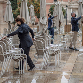 Unos trabajadores de un restaurante del centro de Valencia recogen la terraza. EFE/Biel Aliño