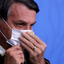 El presidente de Brasil, Jair Bolsonaro, ajustándose la mascarilla.