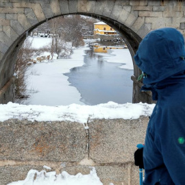 Un hombre observa el río Adaja, prácticamente congelado, a su paso por Ávila.