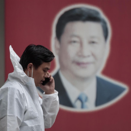 Un hombre con equipo de protección habla por teléfono en la calle, frente al cartel del presidente chino Xi Jinping, en medio del bloqueo de Covid-19 en Shanghái, China, el 23 de mayo de 2022.